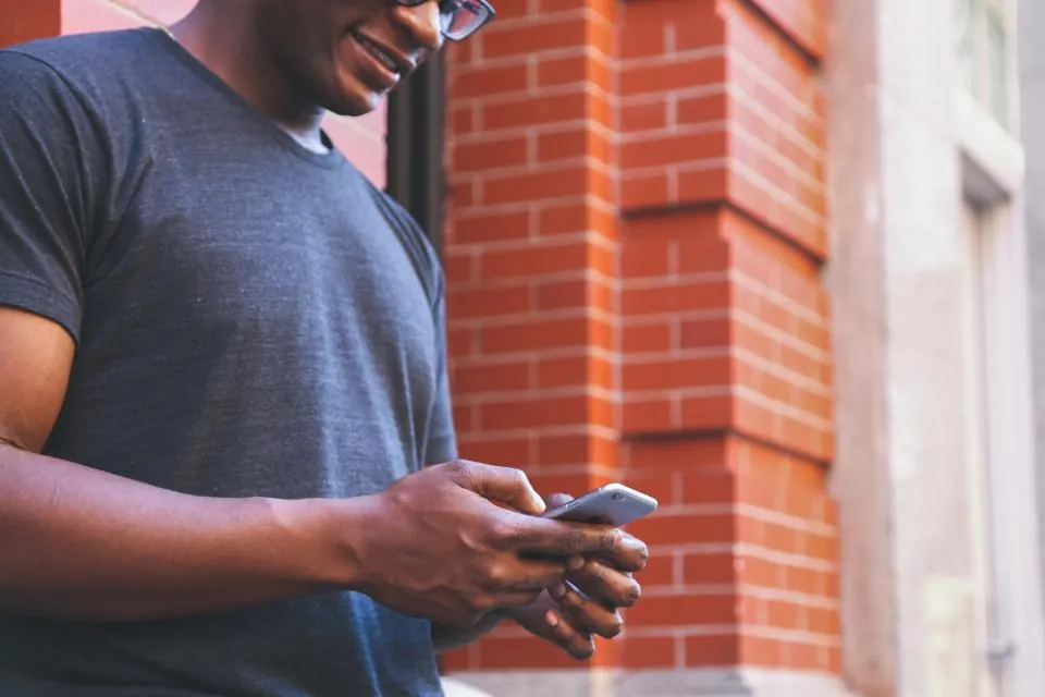 Homme souriant utilisant une application sur son smartphone